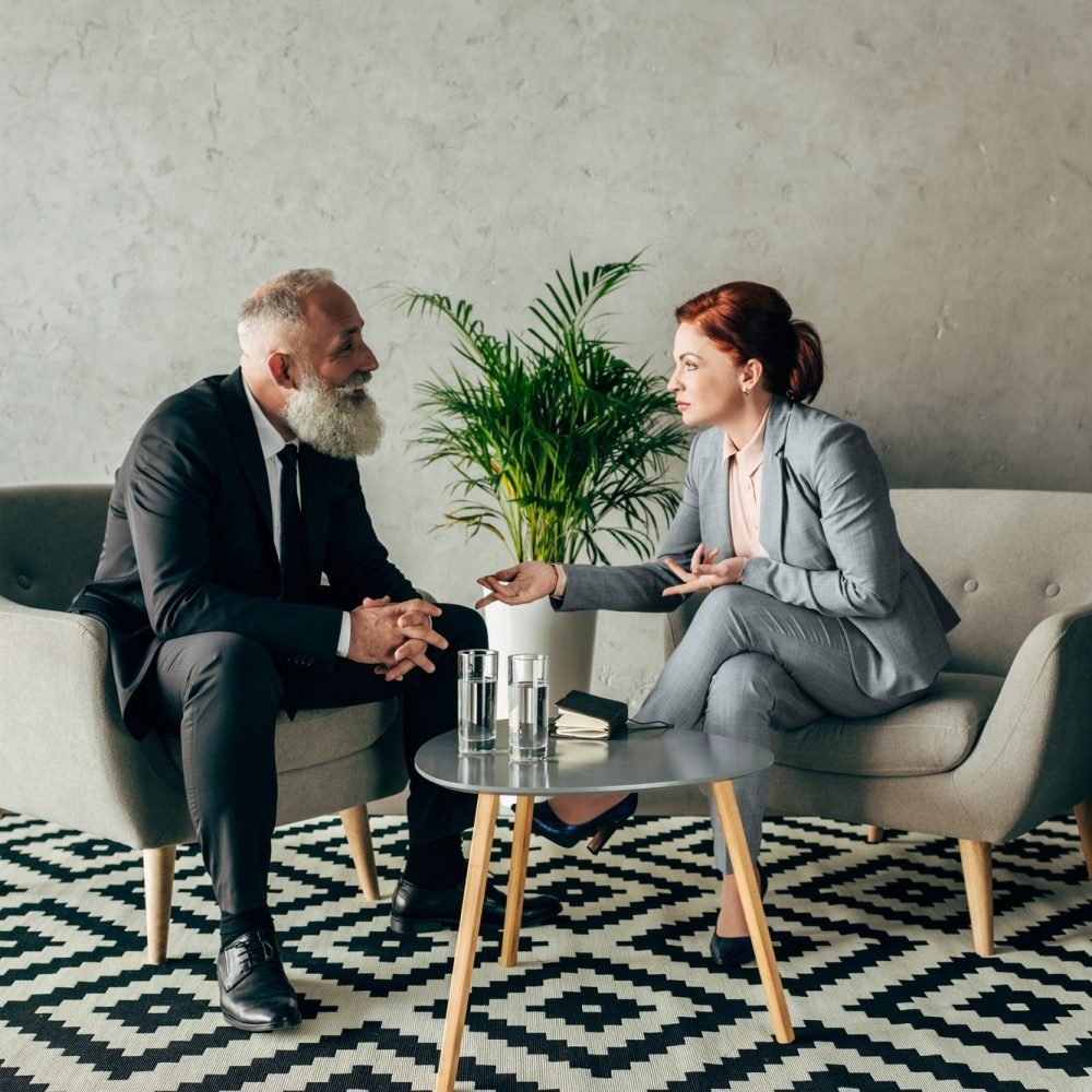 stylish mature business partners conversing in loft office